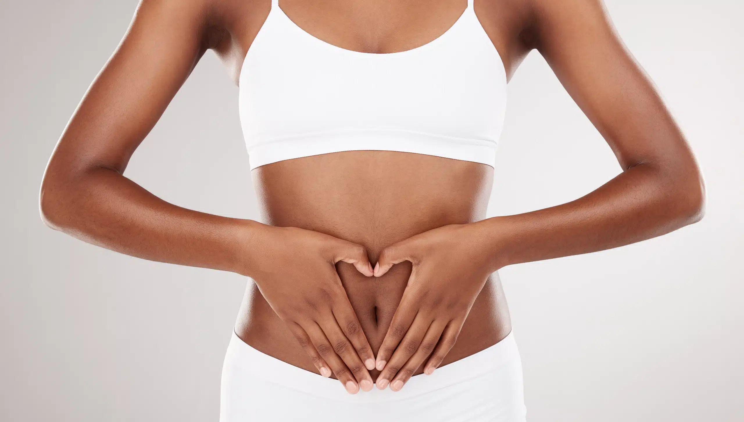 Woman holding her hands over her lower abdomen, representing women’s health, gynecological care, and reproductive wellness with a female gynecologist in the Bronx.
